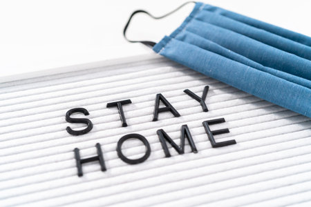 STAY HOME sign on message board with a homemade face mask.