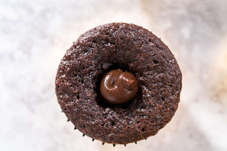 Filling in chocolate cupcakes with chocolate ganache.の写真素材