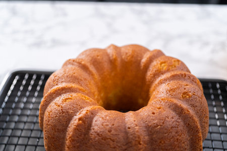 Cooling lemon bundt cake on a kitchen drying rack.
