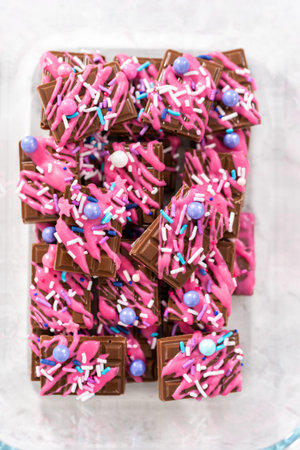 Gourmet dark mini chocolates with drizzled pink chocolate and fancy sprinkles on top.