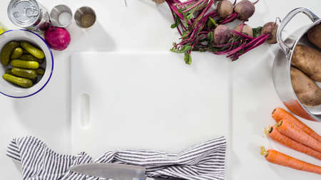 Flat lay. Step by step. Cutting cookies vegetables on a white cutting board for vinaigrette salad.の写真素材