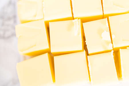 Unsalted butter sticks cut into cubes for preparing Italian buttercream frosting.の写真素材