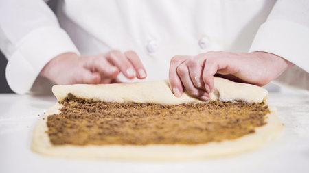 Rolling dough with a french rolling pin to bake cinnamon rolls.