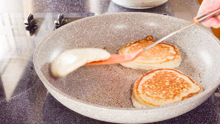 Frying pancakes in a frying pan over the electric stove.の写真素材