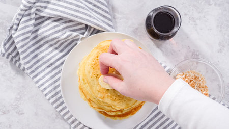 Flat lay. Step by step. Stack of freshly baked coconut banana pancakes garnished with sliced...