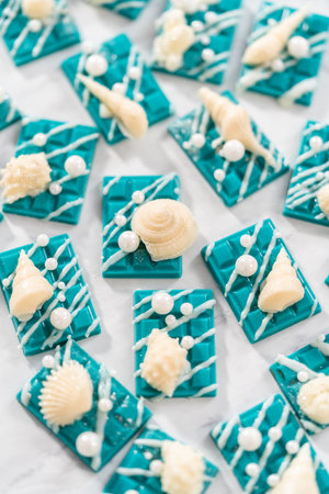 Mini mermaid chocolate bars drizzled with white chocolate, sprinkling with white pearl sugar sprinkles, and decorated with a white chocolate seashells.の写真素材