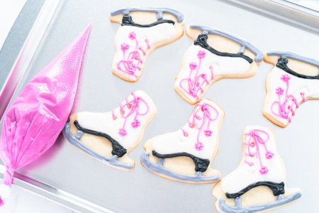 Decorating sugar cookies shaped as figure skates with royal icing.