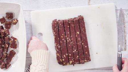 Flat lay. Step by step. Cutting homemade macadamia fudge on a white cutting board.