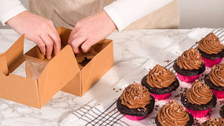 step by step. Packaging chocolate cupcakes with chocolate ganache frosting into a paper cupcake box.の写真素材
