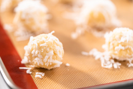 Unbaked dough scoops on the baking sheet to bake coconut cookies.