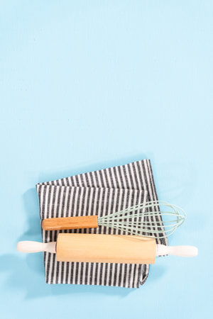 Flat lay. New blue silicone kitchen utensils with wooden handles on a blue background.