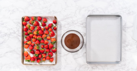 Flat lay. Dipping strawberries into the melted chocolate to prepare chocolate-covered strawberries.