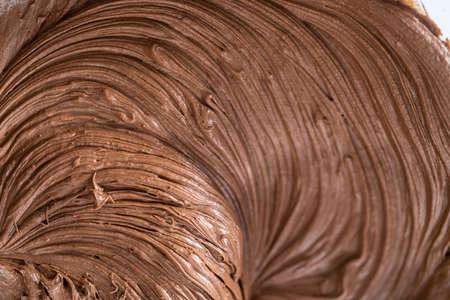 Mixing store-bought chocolate frosting in a mixing glass bowl with a hand mixer.の写真素材