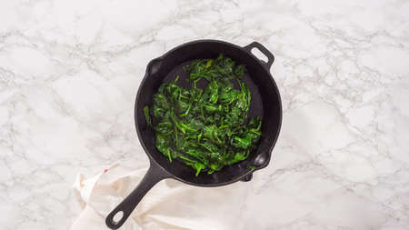 flat lay. step by step. Heating cast iron skillet over the stove to prepare spinach and ham frittata.の写真素材