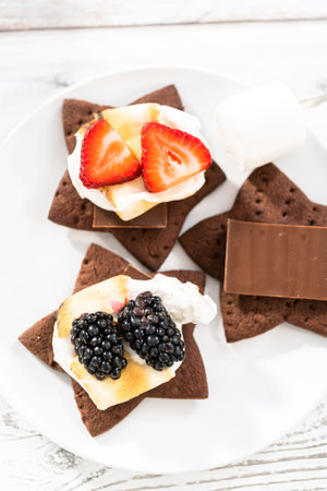 Making s'mores on a homemade star-shaped chocolate graham cracker with toasted marshmallow and...