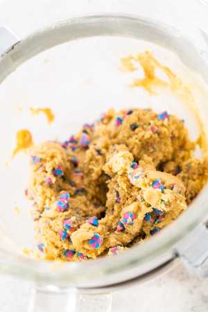 Cookie dough in a glass mixing bowl to prepare unicorn chocolate chip cookies.