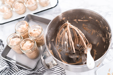 Scooping mixture into the small glass jars to make homemade chocolate ice cream.