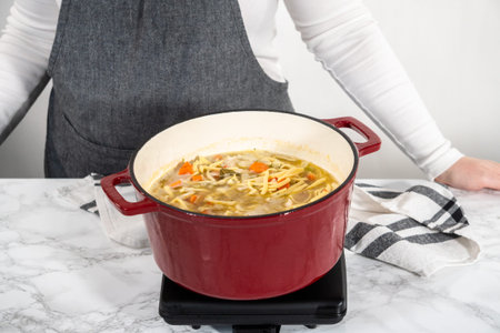 Cooking chicken noodle soup with kluski noodles in an enameled dutch oven.