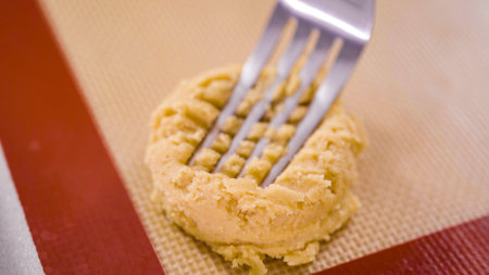 Step by step. Scooping peanut butter cookies dough with dough scooper into the baking sheet.