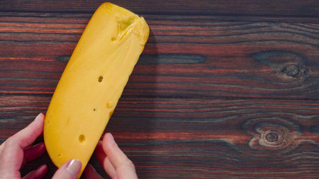 Flat lay. Large wedge of smoked gouda cheese on a rustic wood background.