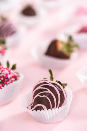 Variety of chocolate dipped strawberries on a pink background.