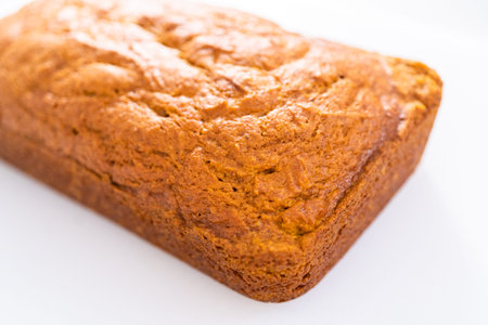 Sliced homemade pumpkin bread on a white cutting board.