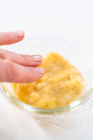 Mashed overripe banana in a glass mixing bowl.の写真素材