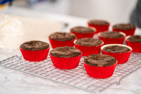 Piping peppermint buttercream frosting on top of the chocolate cupcakes and decorating with crushed...