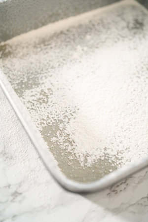 Greasing metal square baking pan to bake sweets.