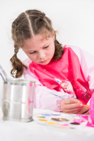 Little girl painting Halloween pumpkin with acrylic paint.