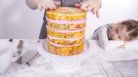 Step by step. Frosting round funfetti cake layers with pink buttercream frosting.の写真素材