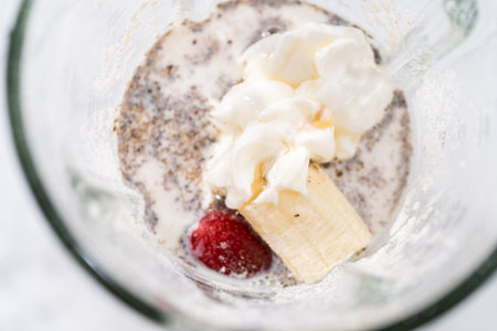 Blending ingredients for healthy breakfast strawberry banana smoothie in a kitchen blender.の写真素材