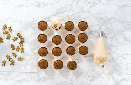 Piping eggnog buttercream frosting on top of gingerbread cupcakes and topping with a chocolate...