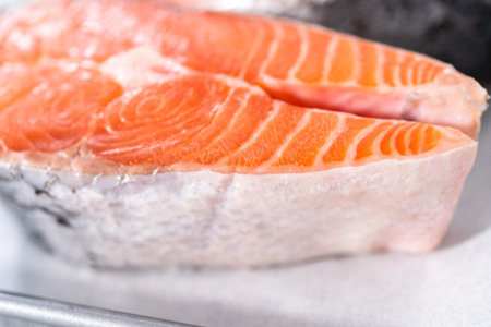 Farm-raised salmon steaks on a cooking tray with a parchment paper.