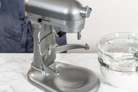 Mixing ingredients in kitchen electric mixer to bake meringue cookies.