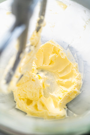 Mixing ingredients in kitchen electric mixer to make lemon buttercream frosting.の写真素材