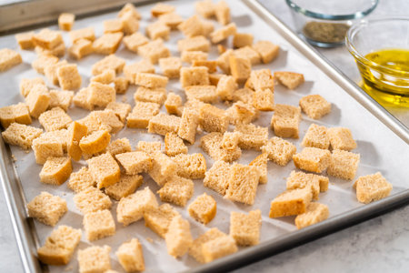 Baking croutons seasoned with olive oil and spiced on a baking sheet lined with parchment paper.の写真素材