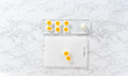 Slicing hard-boiled eggs on a white cutting board.