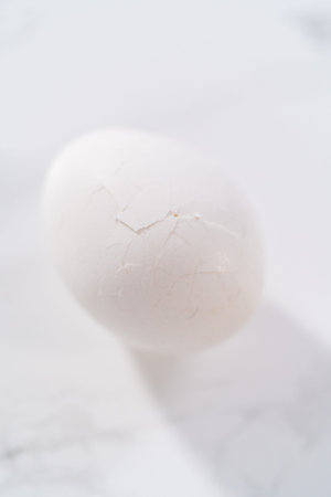 Peeling hard-boiled eggs at the marble kitchen counter.の写真素材