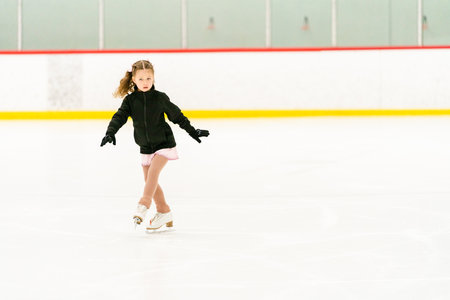 Little girl practicing figure skating on an indoor ice skating rink.の写真素材