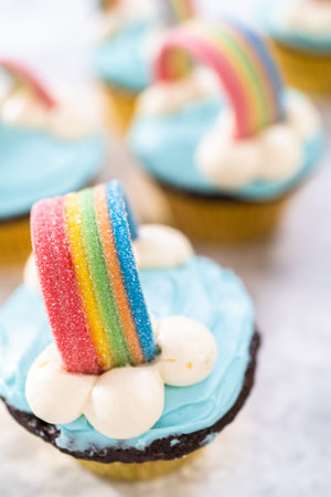 Chocolate cupcakes decorated with blue buttercream frosting and rainbow for unicorn theme birthday...