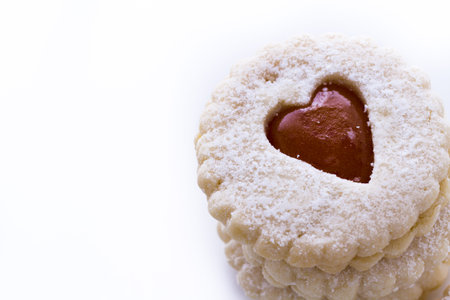 Linzer Torte cookies on white background with powdered sugar sprinkled on top.