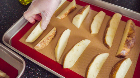 Preparing potato wedges on baking sheet in oven.の写真素材