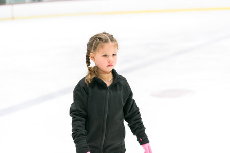Little girl practicing figure skating on an indoor ice skating rink.の写真素材
