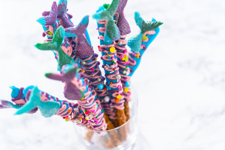 Mermaid chocolate pretzel rods drizzled with pink and purple chocolate and covered with sprinkles.の写真素材