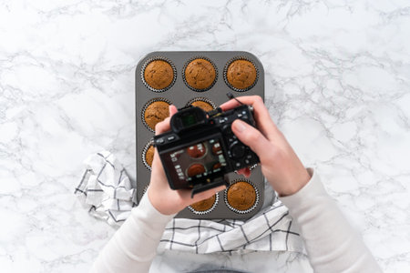 Food photographer photographing baking pan with gingerbread cupcakes.