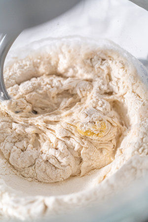 Mixing ingredients in a large glass mixing bowl to pizza dough.の写真素材