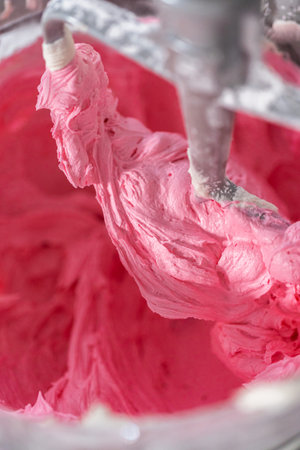 Mixing ingredients in kitchen electric mixer to make ombre pink buttercream frosting.の写真素材