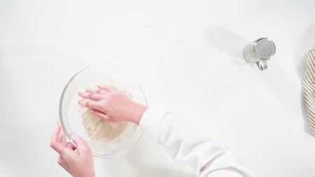 Flat lay. Knitting dough by hand to bake cinnamon rolls.