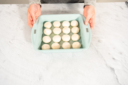 Preparing dinner rolls from the frozen dough in baking pan.
